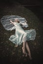Barefoot bride lie on gras and leaves with veil around her Royalty Free Stock Photo