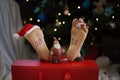 barefoot child lies near the Christmas tree with garlands. The numbers 2023 are painted on fee