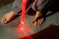 Barefoot in the dark armed with a toy red lightsaber. Star Wars Game Toy lightsaber. Hippie Jedi Knight at night in neon red light Royalty Free Stock Photo