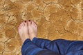 Barefoot female feet in jeans stand on dry cracked ground