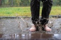 Barefoot female feet jump in a puddle, after rain, dirty water spray scatters in different directions. Photo in motion