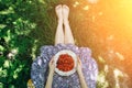 Barefoot girl is sitting on the grass in blue vintage dress. Woman is holding plate with home strawberries. Rustic summer fruit Royalty Free Stock Photo