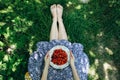 Barefoot girl is sitting on the grass in blue vintage dress. Woman is holding plate with home strawberries. Rustic summer fruit Royalty Free Stock Photo