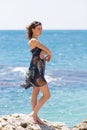 Barefoot girl in sundress posing on rocky seashore Royalty Free Stock Photo