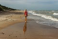 Barefoot Girl walking on beach in Latvia.Sunny day by Baltic Sea.Cold water,wild waves.Solo female traveler enjoying her vacation. Royalty Free Stock Photo