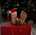 barefoot kid lies in front of the Christmas tree, the numbers 2023 are written on his feet, a souvenir of Santa