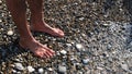 Barefoot male feet stands on a pebble beach washed by the sea. Concept. Close up of man legs and feet under water Royalty Free Stock Photo
