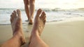 The man feet relaxed are lying on the sandy beach and washed by Royalty Free Stock Photo