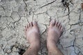 Barefoot standing on dry and cracked ground