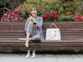 Barefoot woman sits on bench in park and communicates on a smartphone