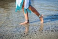 Barefoot woman walking in a river shallow water boho style dress and legs jewelry close up summer day