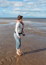 Barefoot woman wearing jeans and grey jumper jumping on beach Royalty Free Stock Photo