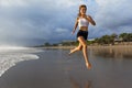 Sporty girl running by beach along sea surf Royalty Free Stock Photo