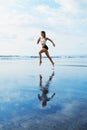 Sporty girl running by beach along sea surf Royalty Free Stock Photo