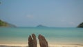 Barefoot young man removes sand from foot lying on beach Royalty Free Stock Photo