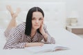 Barefoot young teenage girl looking at the camera lying on her bed reading a book Royalty Free Stock Photo