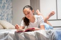 Barefoot young teenage girl lying on her bed reading Royalty Free Stock Photo