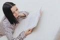 Barefoot young teenage girl lying on her bed reading a book or studying Royalty Free Stock Photo