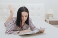 Barefoot young teenage girl lying on her bed reading a book or studying Royalty Free Stock Photo