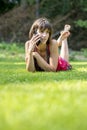 Barefoot young woman chatting on a mobile phone as she lies on h Royalty Free Stock Photo