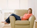 Barefoot young woman lounging on armchair at home Royalty Free Stock Photo