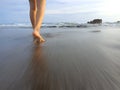 Barefoot of young woman walking on black sand beach. Relax feet or legs of a girl take a walk on beach in the morning Royalty Free Stock Photo