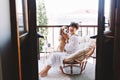 Barefooted laughing girl looking at camera, holding beagle dog while sitting in cozy chair. Lovely young lady with brown