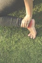 Barefooted Runner woman sit on grass in the park  touching painful twisted or broken ankle. Athlete runner training accident Royalty Free Stock Photo