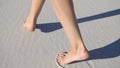 Barefooted woman walks on white sand in a sunny day