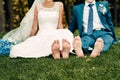 Barefooted young fair-haired bride and her fiance sits on the grass in an exotic park Royalty Free Stock Photo