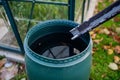 Barell under downspout collecting rainwater from roof in garden. Concept of water conservation.