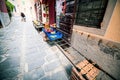 Barga, Tuscany, narrow alley with original local produce shows. An elderly lady sweeps the street in front of the store.