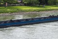 A barge carrying fine coal on the Rhine in western Germany with a lawn in the background.