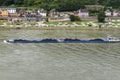 A barge with coal sailing on the river Rhine in western Germany, visible buildings on the river bank, aerial view.