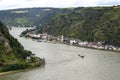 Barge with a covered deck sailing on the river Rhine in western Germany, visible buildings on the river bank, aerial view.