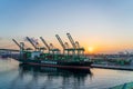 a barge docked in a port with cargo cranes next to it