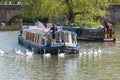 Barge and narrowboat pass each other surrounded by swans on a lake uin England during the summer