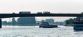 Barge on a river goes under a bridge with trucks