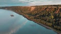 A barge with a tug is moving along the river Ob against the backdrop of a hill