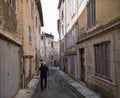 Old man with walking stick walks through old street in medieval town of bargemon in the french provence