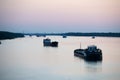 barges and fishing and merchant ships on the river at dusk against the background of wires and poles