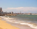 Sand beach of Mediterranean sea with city panorama of Bari. Coastline with waves and embankment.