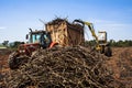 A tractor with a lifting claw loading a truck with sugar cane