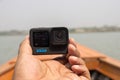 Barisal, Bangladesh - March 12, 2023, Modern action camera close up shot on hand and a blurry river view. Professional action