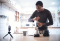 Barista African American man streaming virtual video online of making drip coffee with smartphone at home inside kitchen. Black