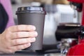 Barista in an apron holds hot coffee