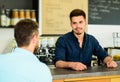 Barista at bar of modern cafe ready to serve coffee for client. Man ask for coffee at bar counter. Barista handsome