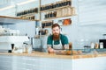 Barista with beard and moustache standing in coffee shop