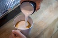 Barista in cafe or coffee bar preparing proper cappuccino pouring milk froth in a cup. Waiter hands pouring milk making cappuccino Royalty Free Stock Photo