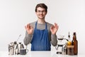 Barista, cafe worker and bartender concept. Portrait of satisfied, pleased young male employee in apron smiling assuring